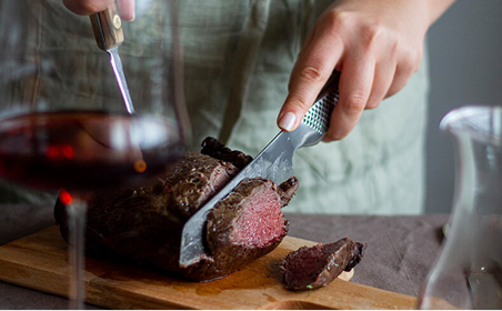 Skivar kött med kniv på skärbräda