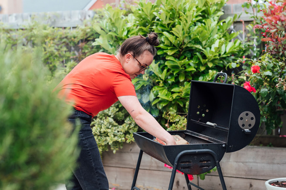 Kvinna böjer sig fram mot en grill