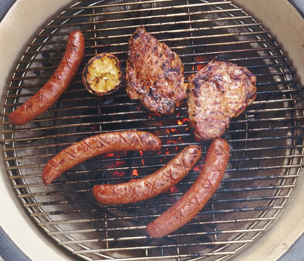 Klotgrill uppifrån med korv och kött på gallret