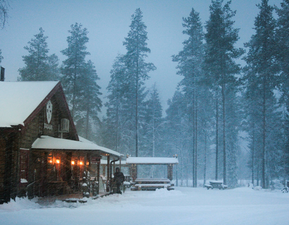 Hus och skog i mörkret med snö