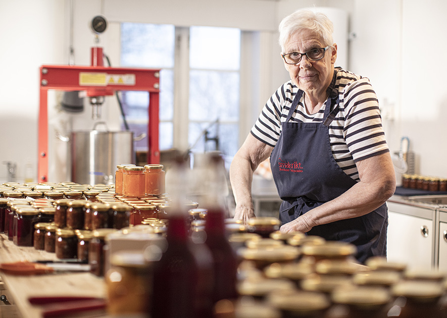 Berit framför marmeladburkar i köket