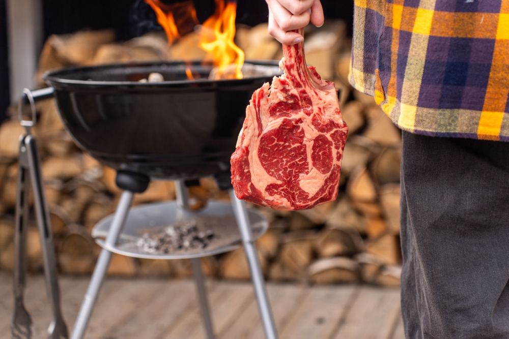 Kvinna håller i en tomahawk vid grillen