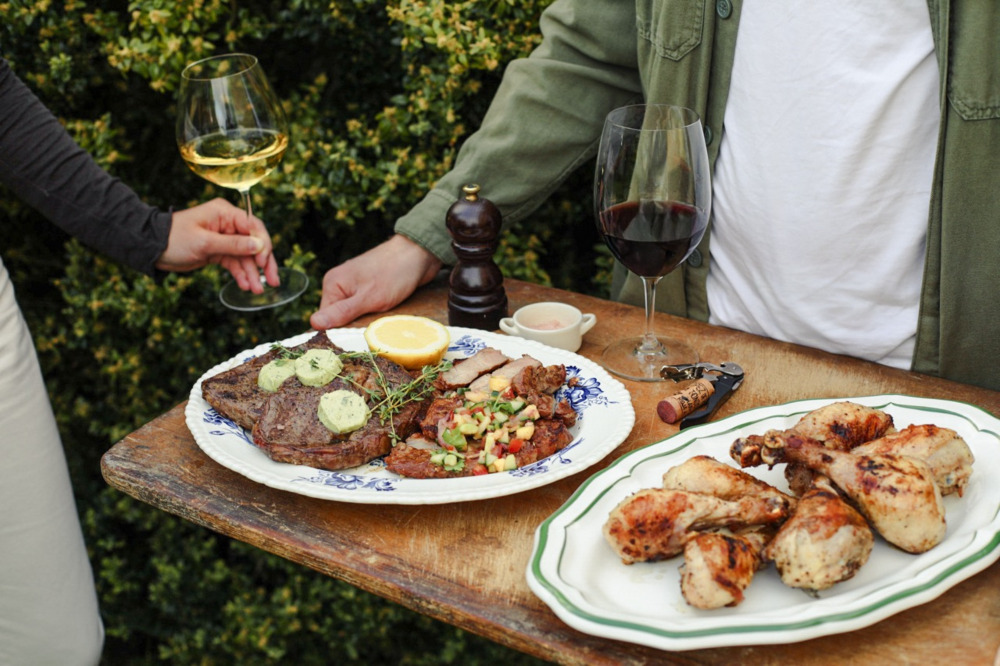 Bricka med k&ouml;tt och kyckling, vinglas i bakgrunden