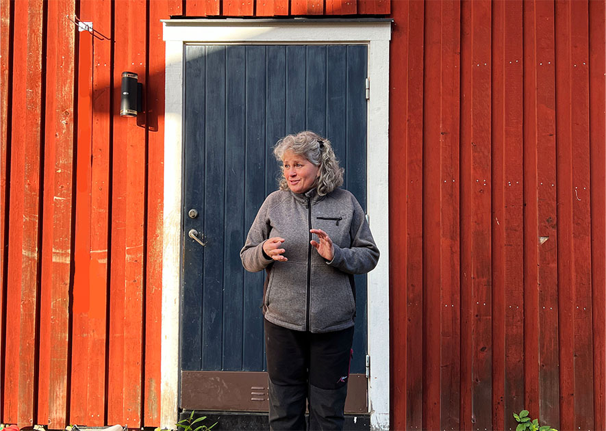 Kvinna framför rött trähus