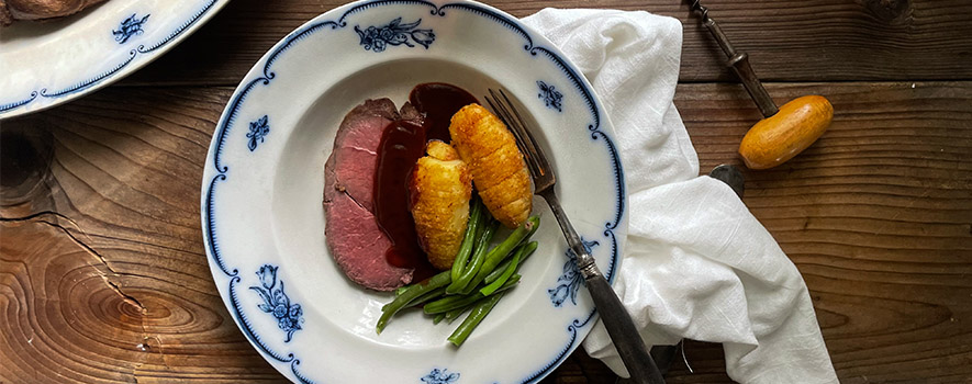 Vildsvinsstek på tallrik med hasselbackspotatis och rödvinssås