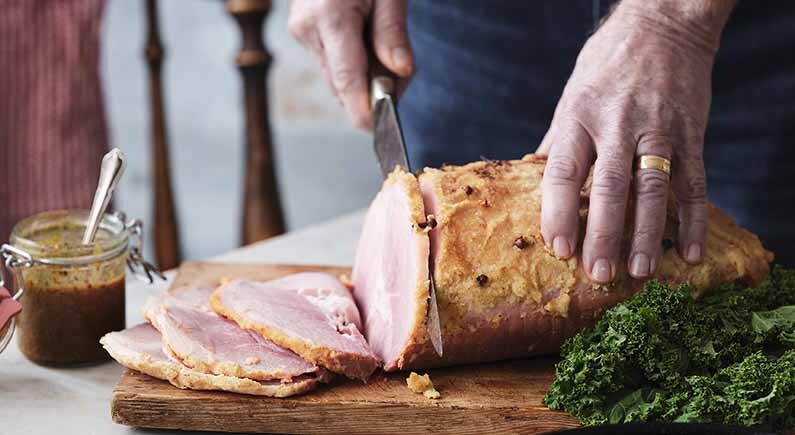 Händer som skär julskinka med kniv