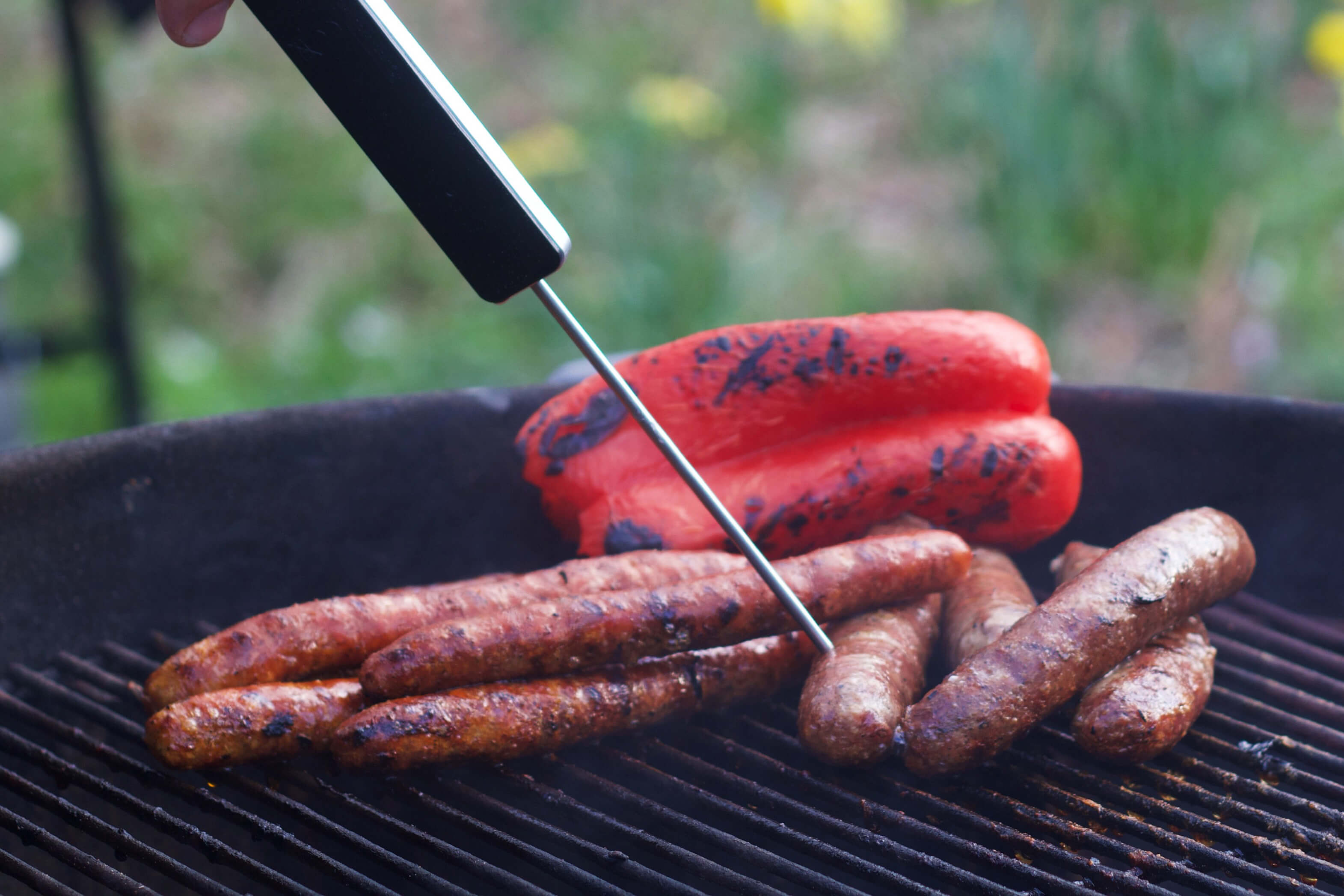 Korv och paprika på en grill med en stektermometer